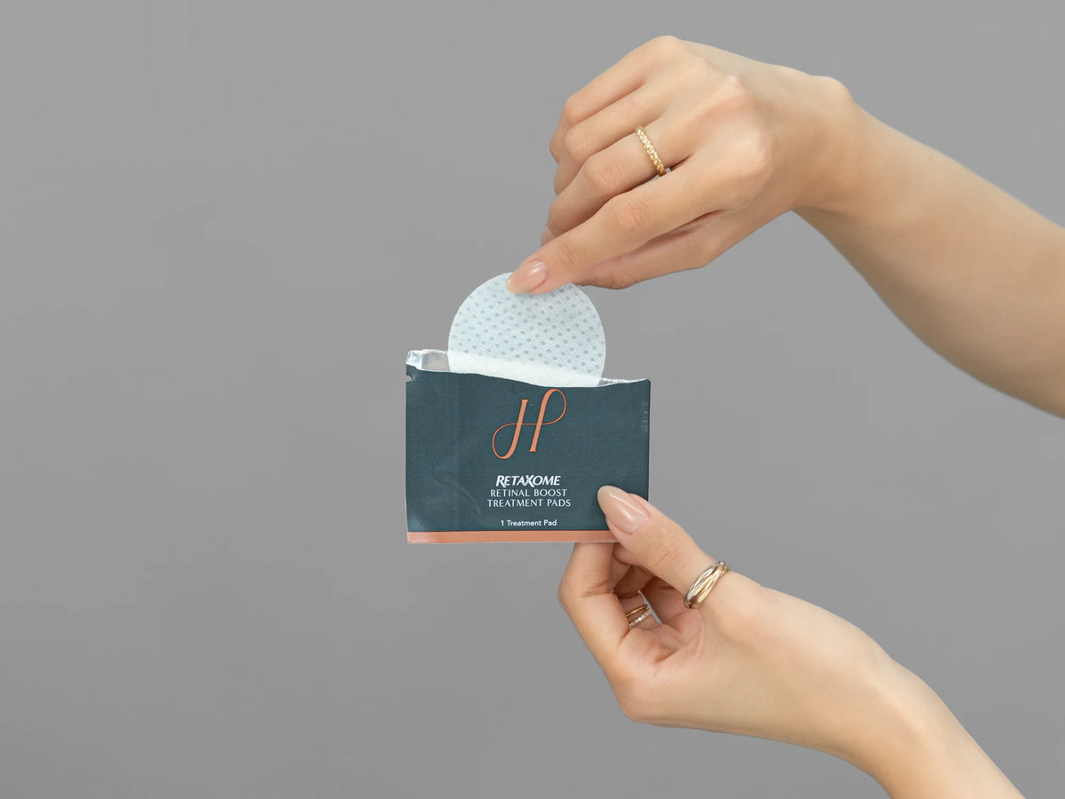 Closeup of Laziza from LAZ Skincare holding up a bottle of Hydrinity RetaXome Retinal Boost Treatment Pads