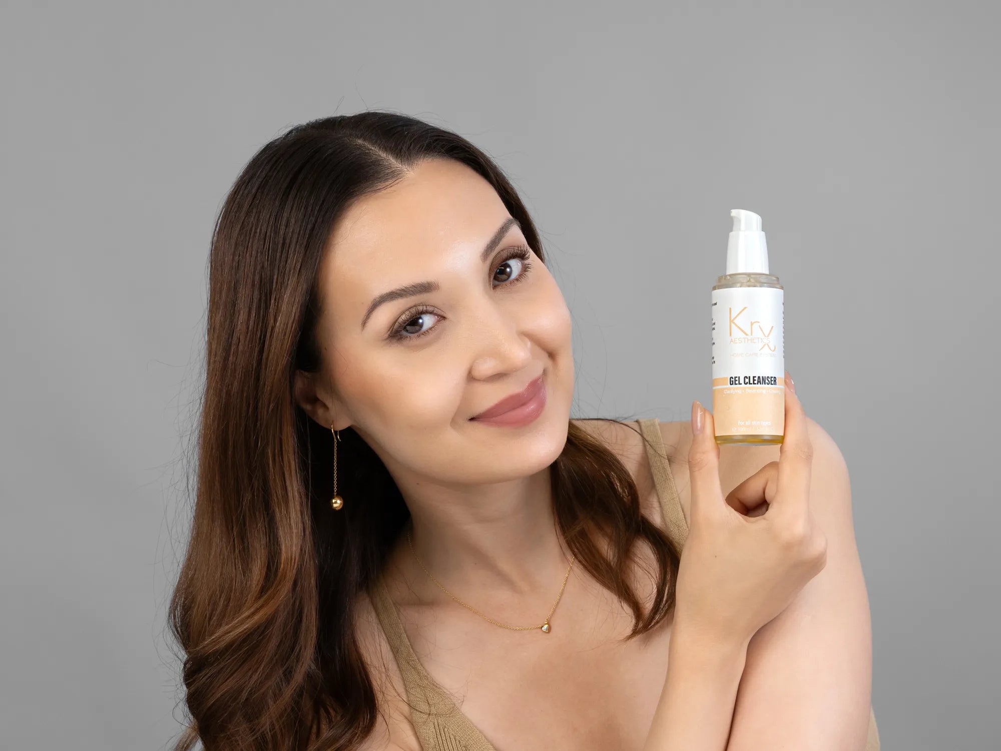 Laziza from LAZ Skincare holding a bottle of KrX Aesthetics Glow Gel Cleanser up to her face