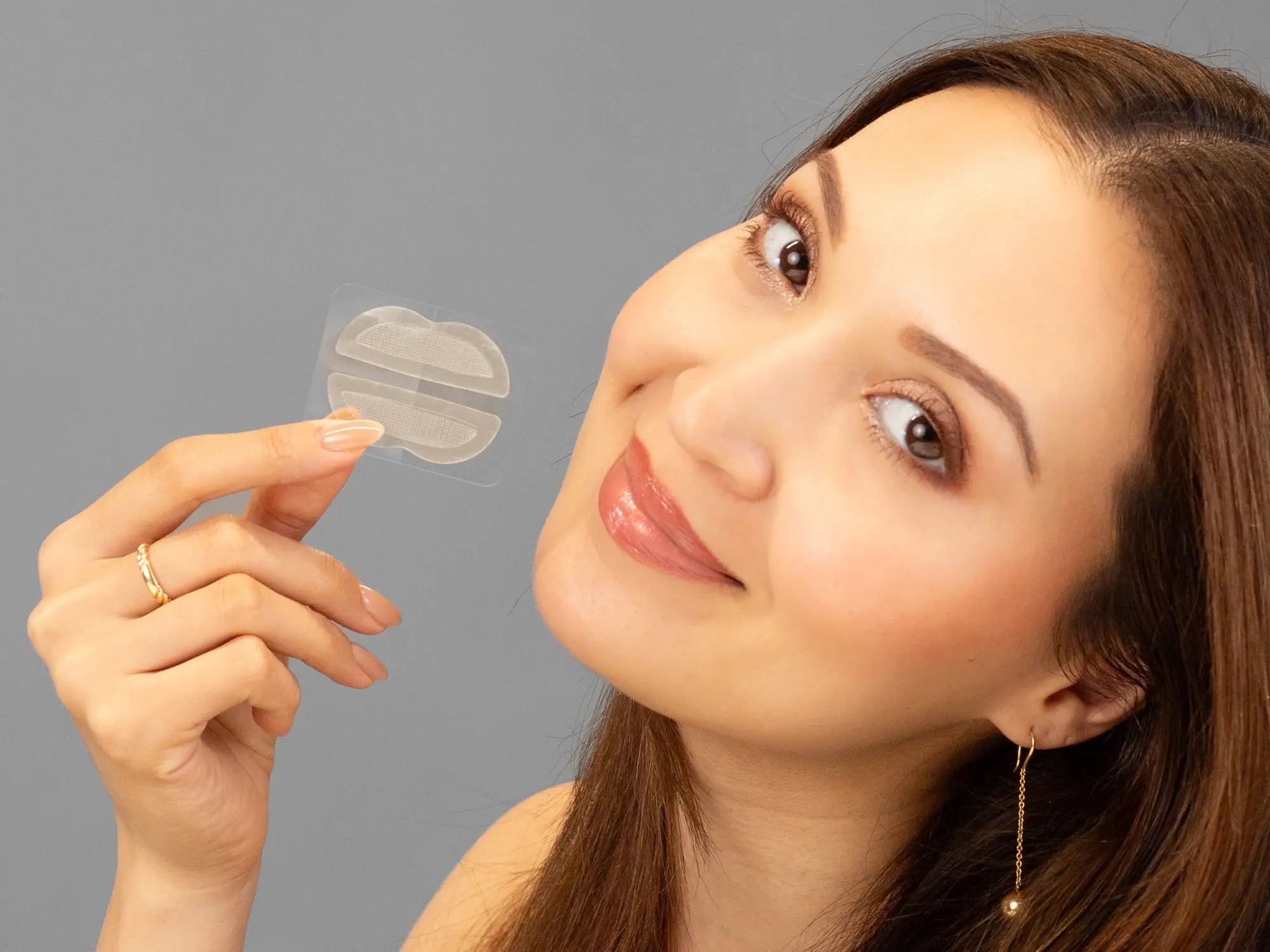 Laziza from LAZ Skincare holding a bottle of KrX Aesthetics Lip Darts up to her face