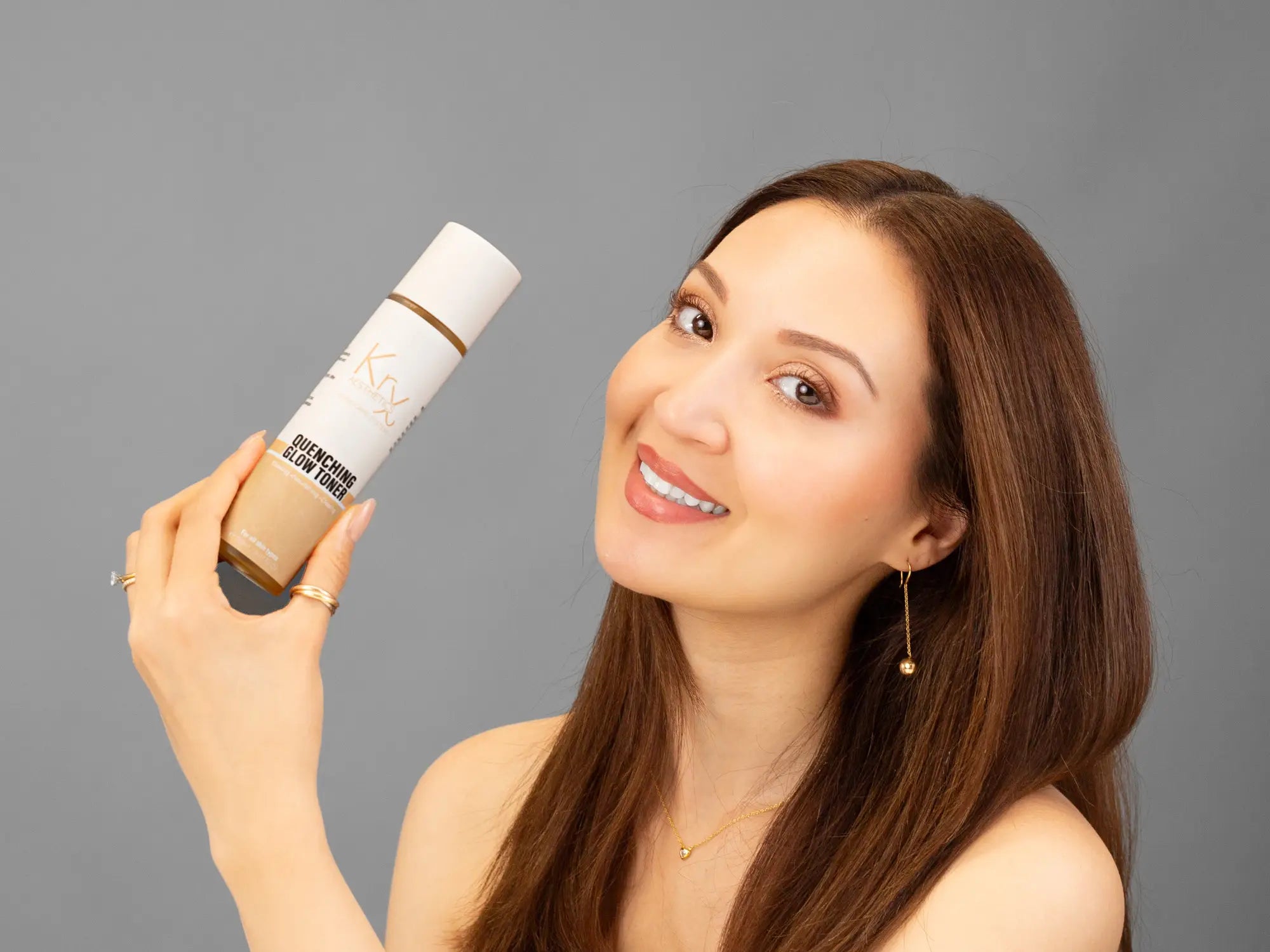Laziza from LAZ Skincare holding a bottle of KrX Aesthetics Quenching Glow Toner up to her face