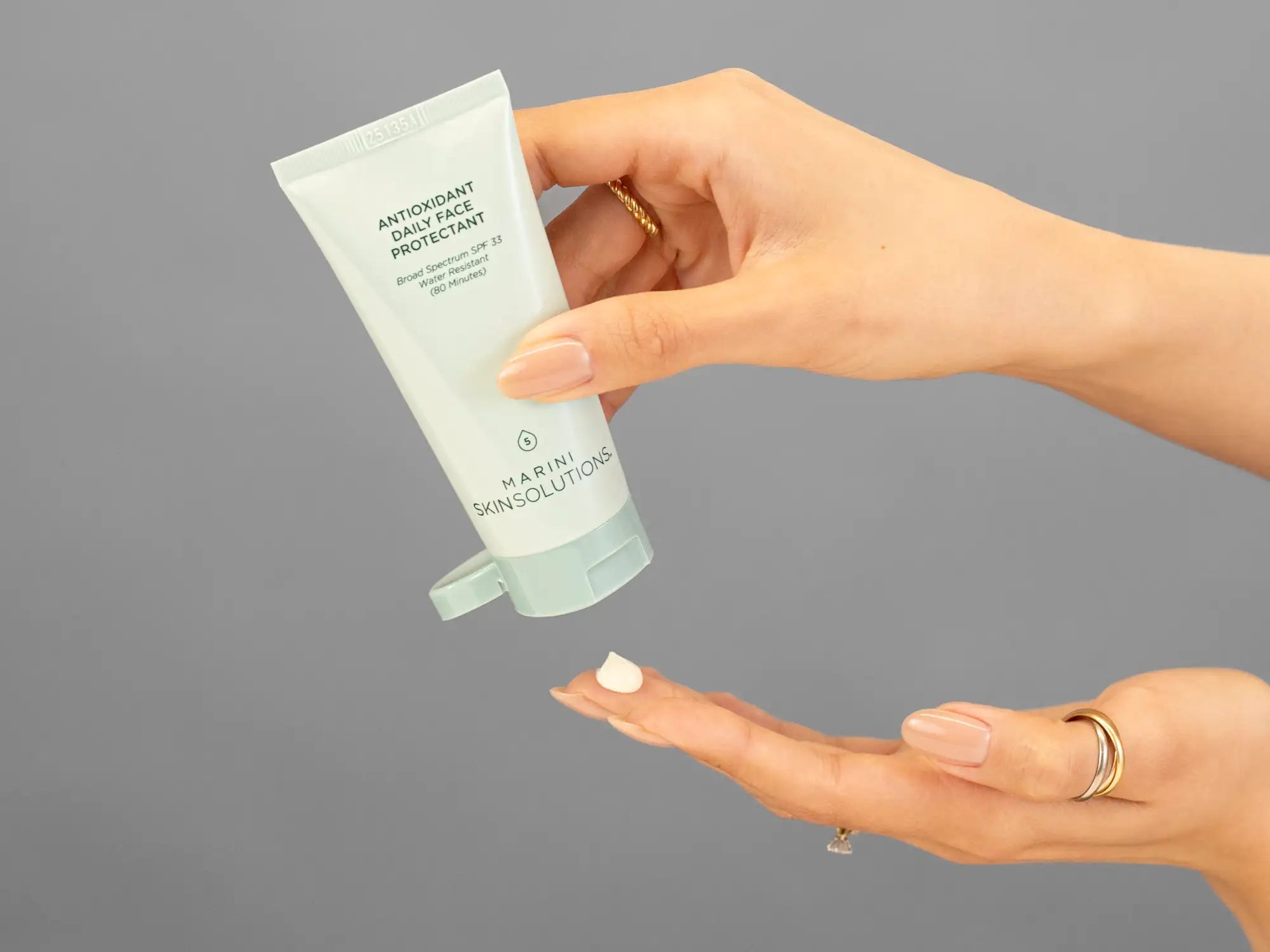 Closeup of Laziza from LAZ Skincare holding up a bottle of Marini SkinSolutions Antioxidant Daily Face Protectant SPF 33