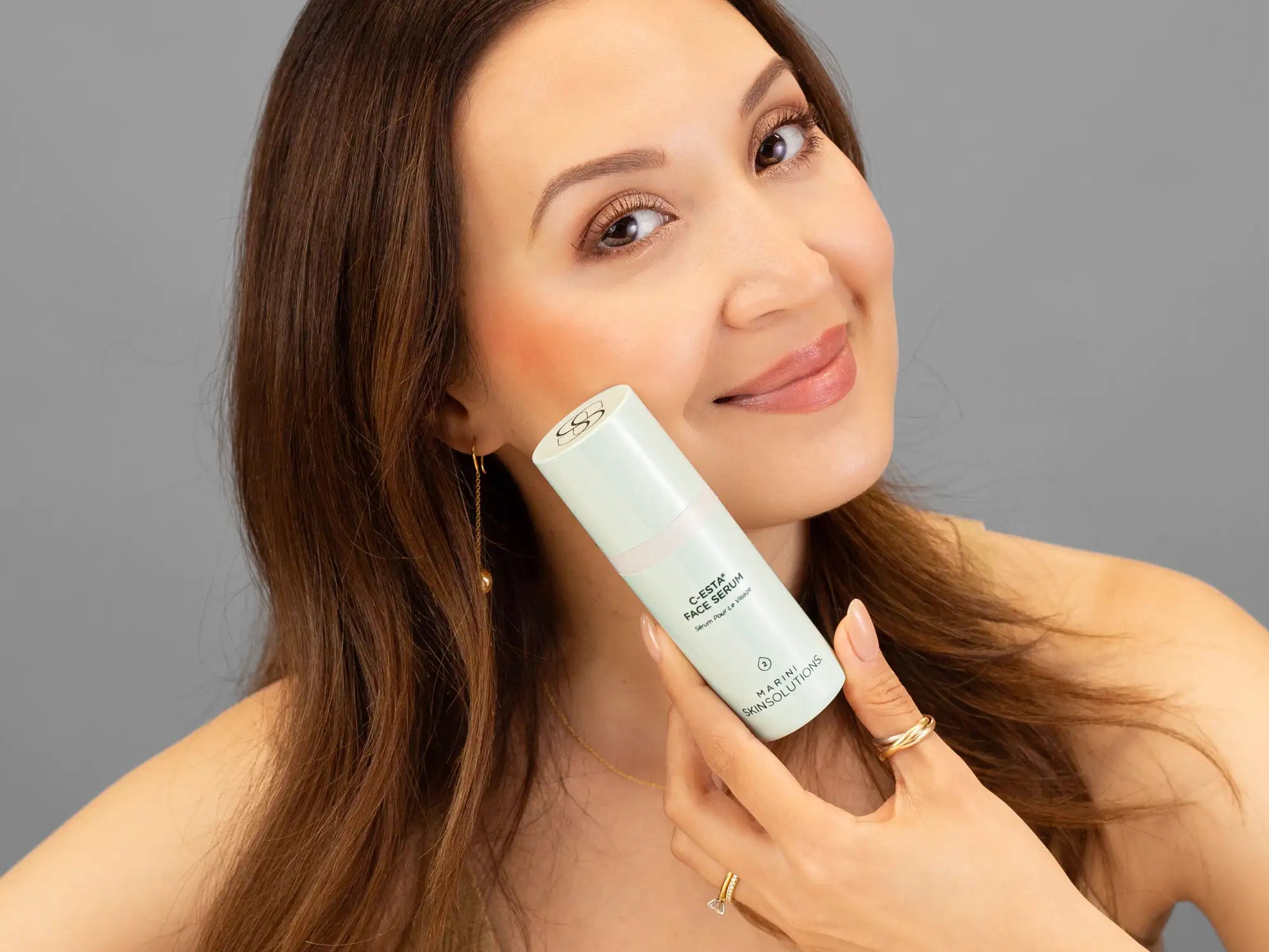 Laziza from LAZ Skincare holding a bottle of Marini SkinSolutions C-Esta Face Serum up to her face