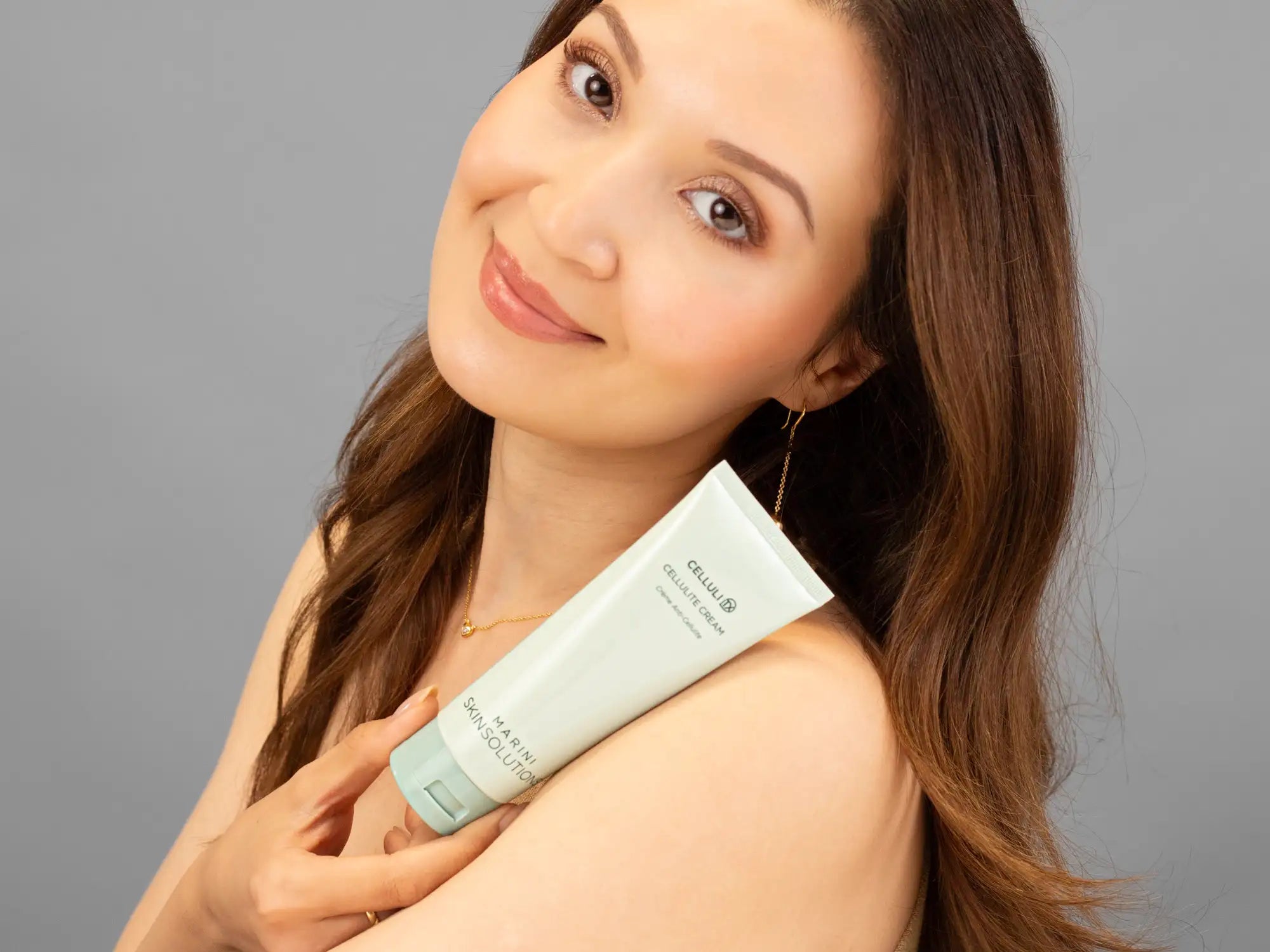 Laziza from LAZ Skincare holding a bottle of Marini SkinSolutions CelluliTx up to her face