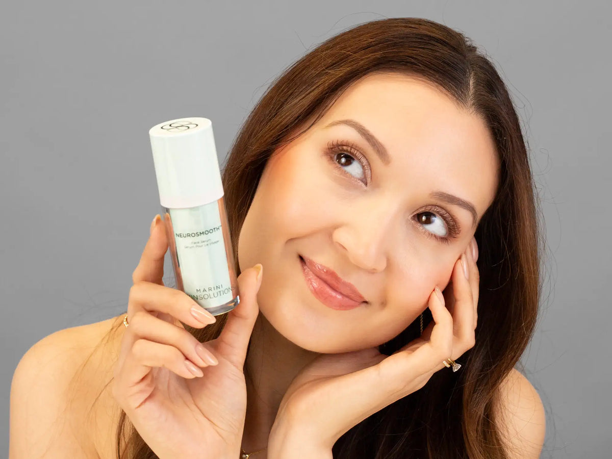 Laziza from LAZ Skincare holding a bottle of Marini SkinSolutions NeuroSmooth up to her face