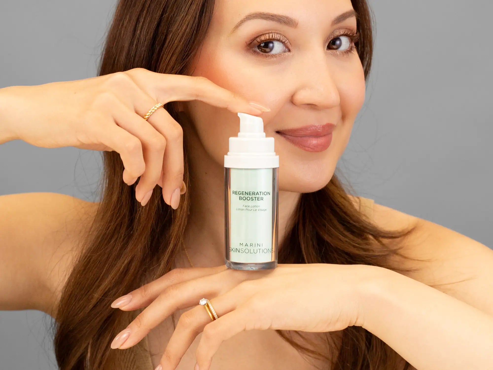 Laziza from LAZ Skincare holding a bottle of Marini SkinSolutions Regeneration Booster up to her face