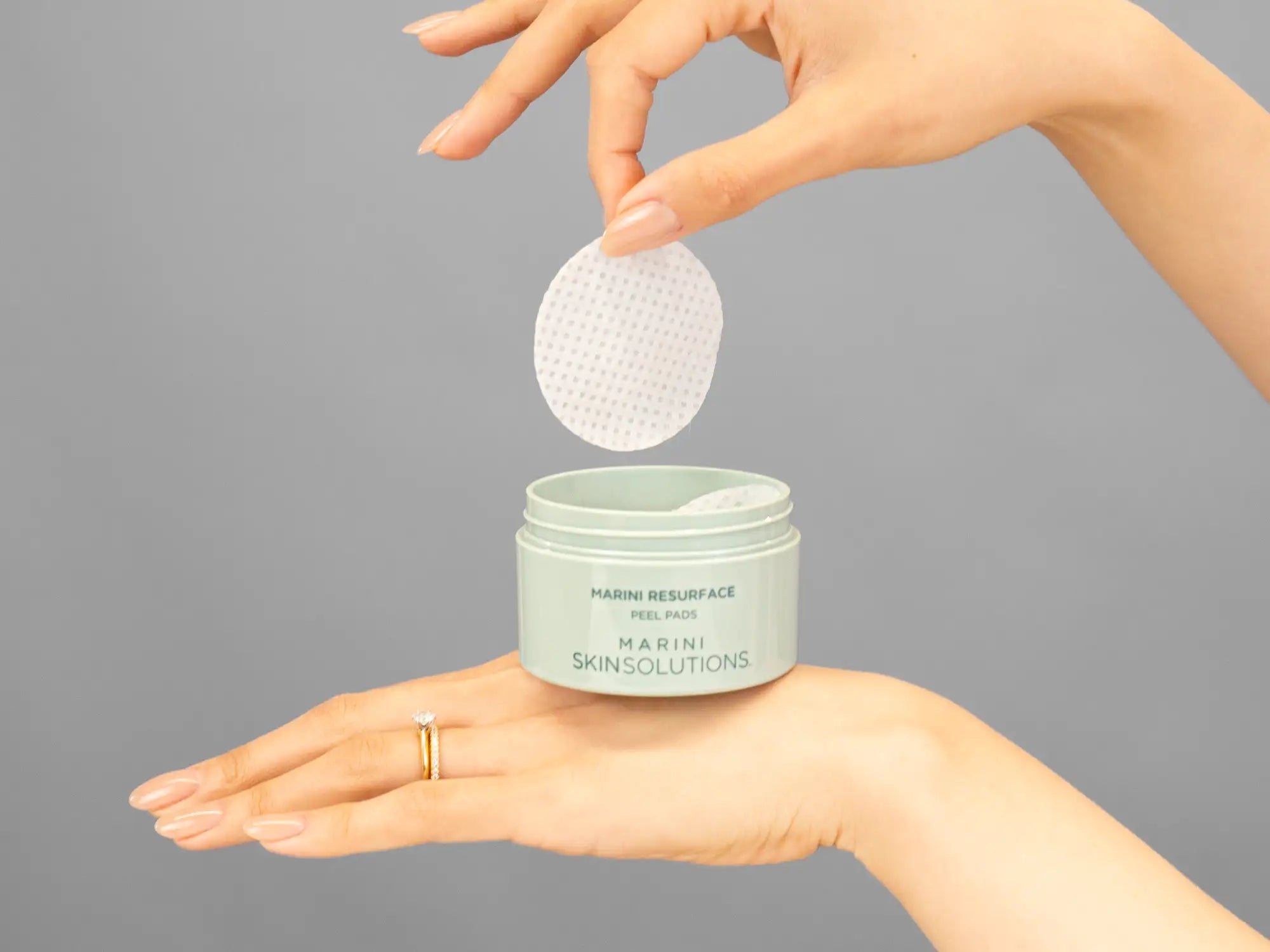 Closeup of Laziza from LAZ Skincare holding up a bottle of Marini SkinSolutions Marini Resurface Peel Pads