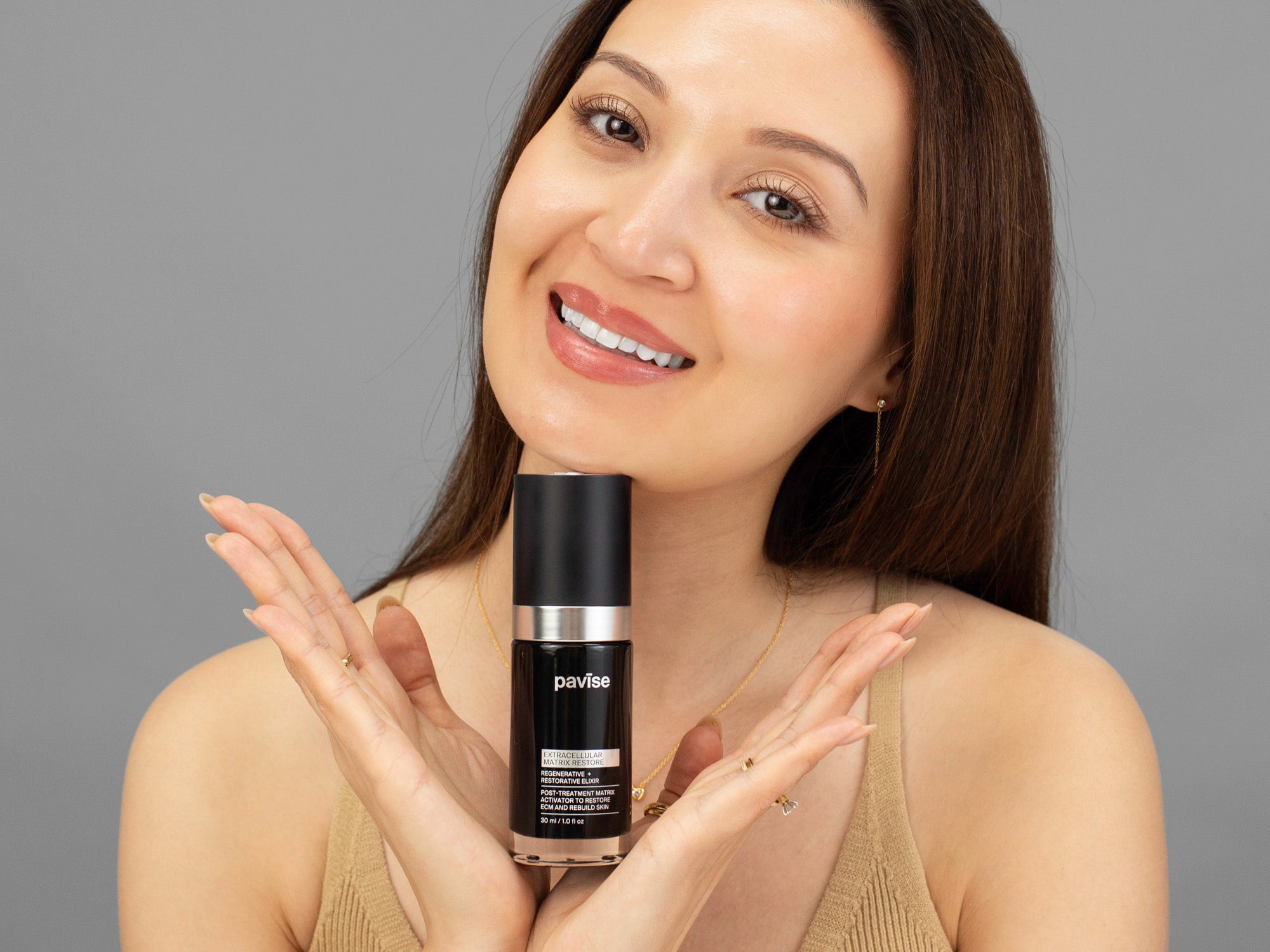 Laziza from LAZ Skincare holding up a bottle of Pavise Extracellular Matrix Restore