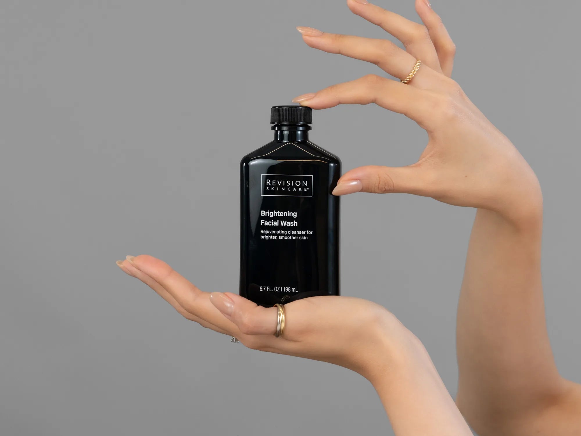 Closeup of Laziza from LAZ Skincare holding up a bottle of Revision Brightening Facial Wash