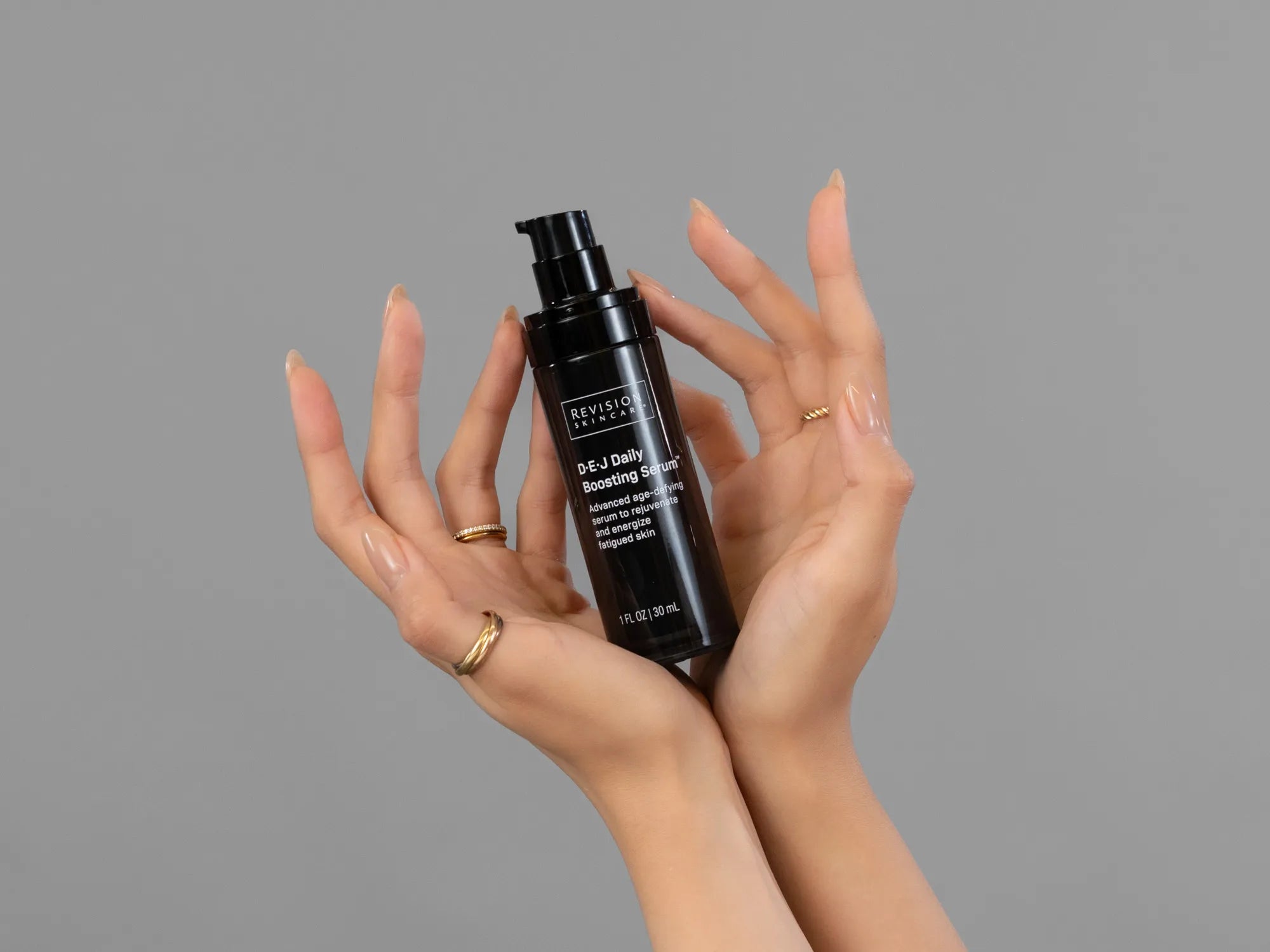 Closeup of Laziza from LAZ Skincare holding up a bottle of Revision D·E·J Daily Boosting Serum