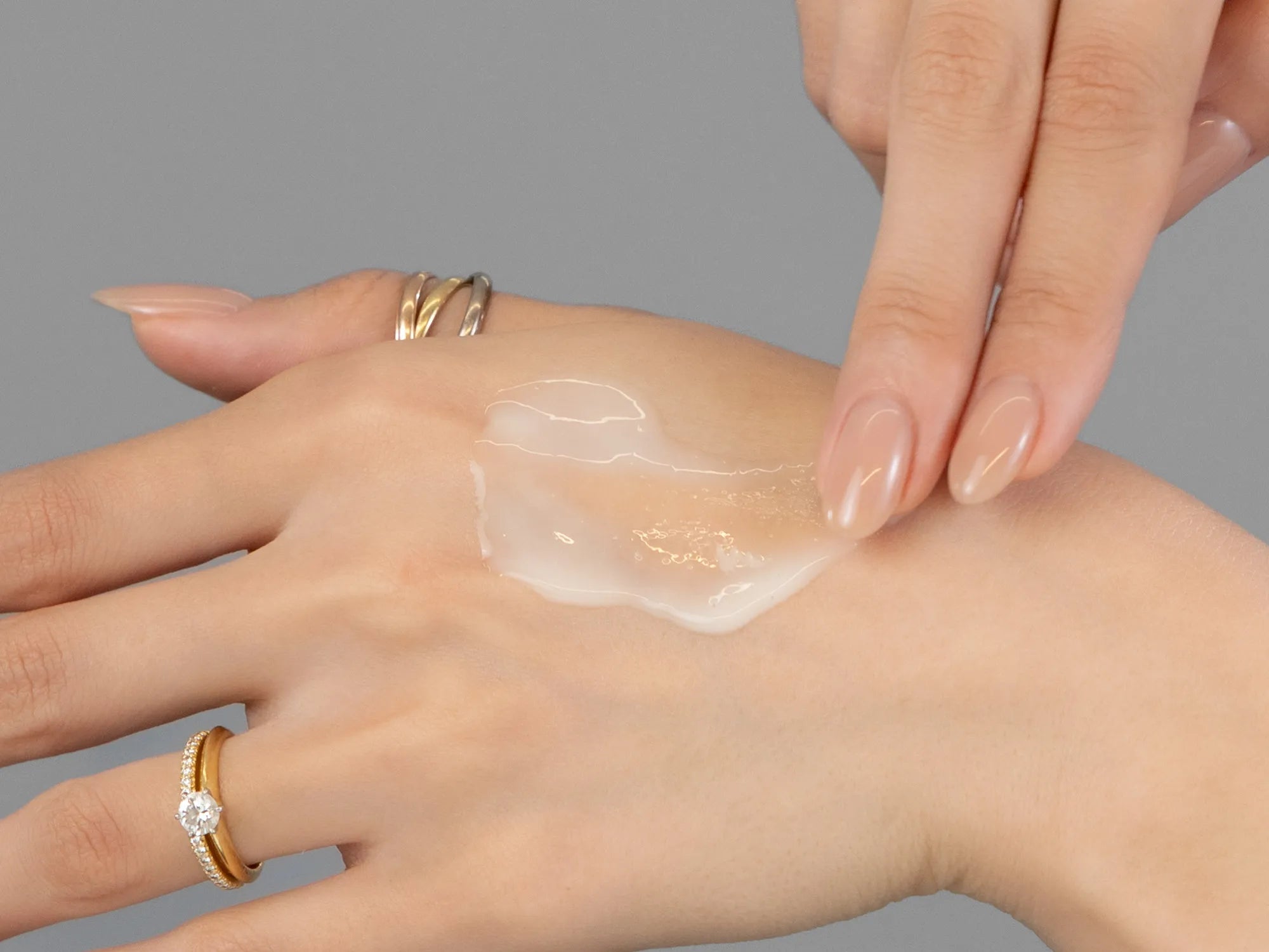Laziza from LAZ Skincare demonstrating the texture and application of Revision D·E·J Daily Boosting Serum on her hand