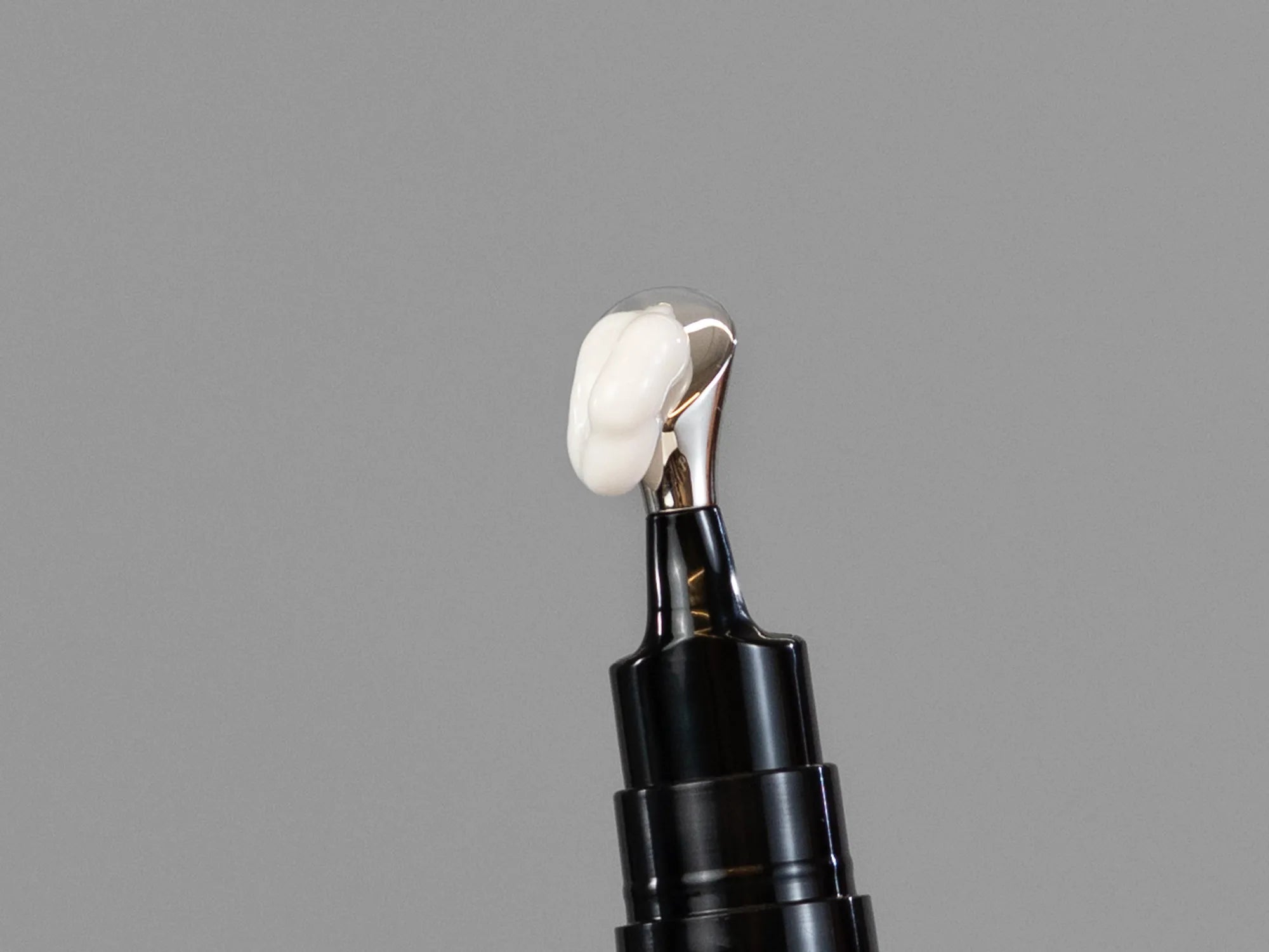 Closeup of Laziza from LAZ Skincare holding up a bottle of Revision D·E·J Eye Cream
