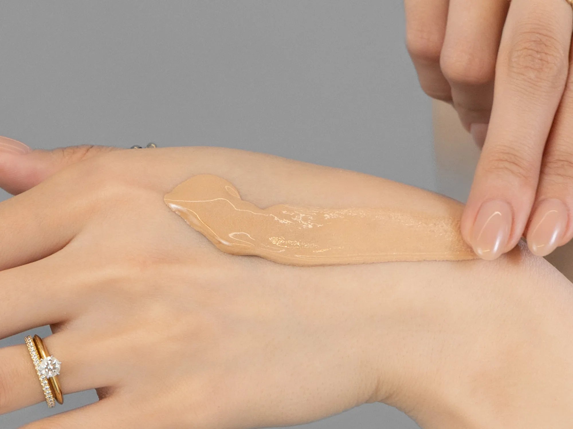 Laziza from LAZ Skincare demonstrating the texture and application of Revision Intellishade Original SPF 45 on her hand