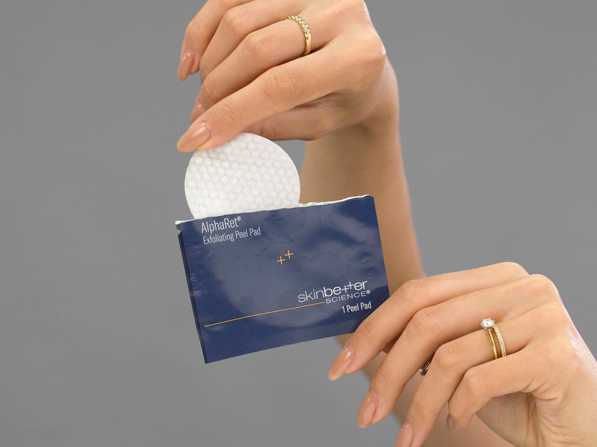 Closeup of Laziza from LAZ Skincare taking a pad out of packet of Skinbetter Science AlphaRet Exfoliating Peel Pads