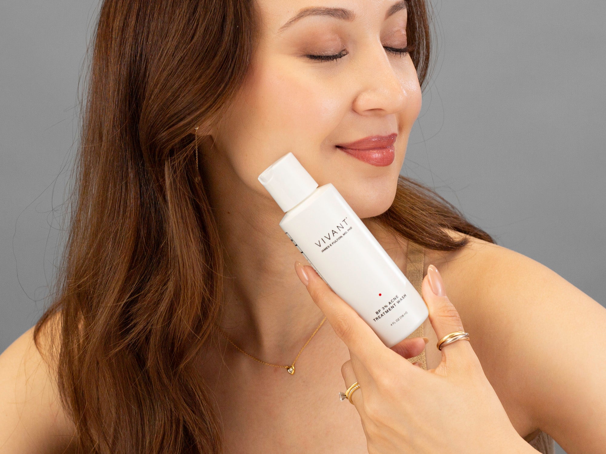 Laziza from LAZ Skincare holding a bottle of Vivant BP 3% Acne Wash up to her face