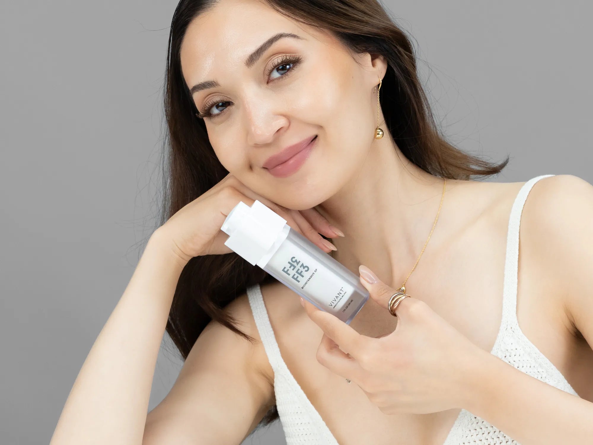 Laziza from LAZ Skincare holding a bottle of Vivant FF3 Biointensive GF up to her face