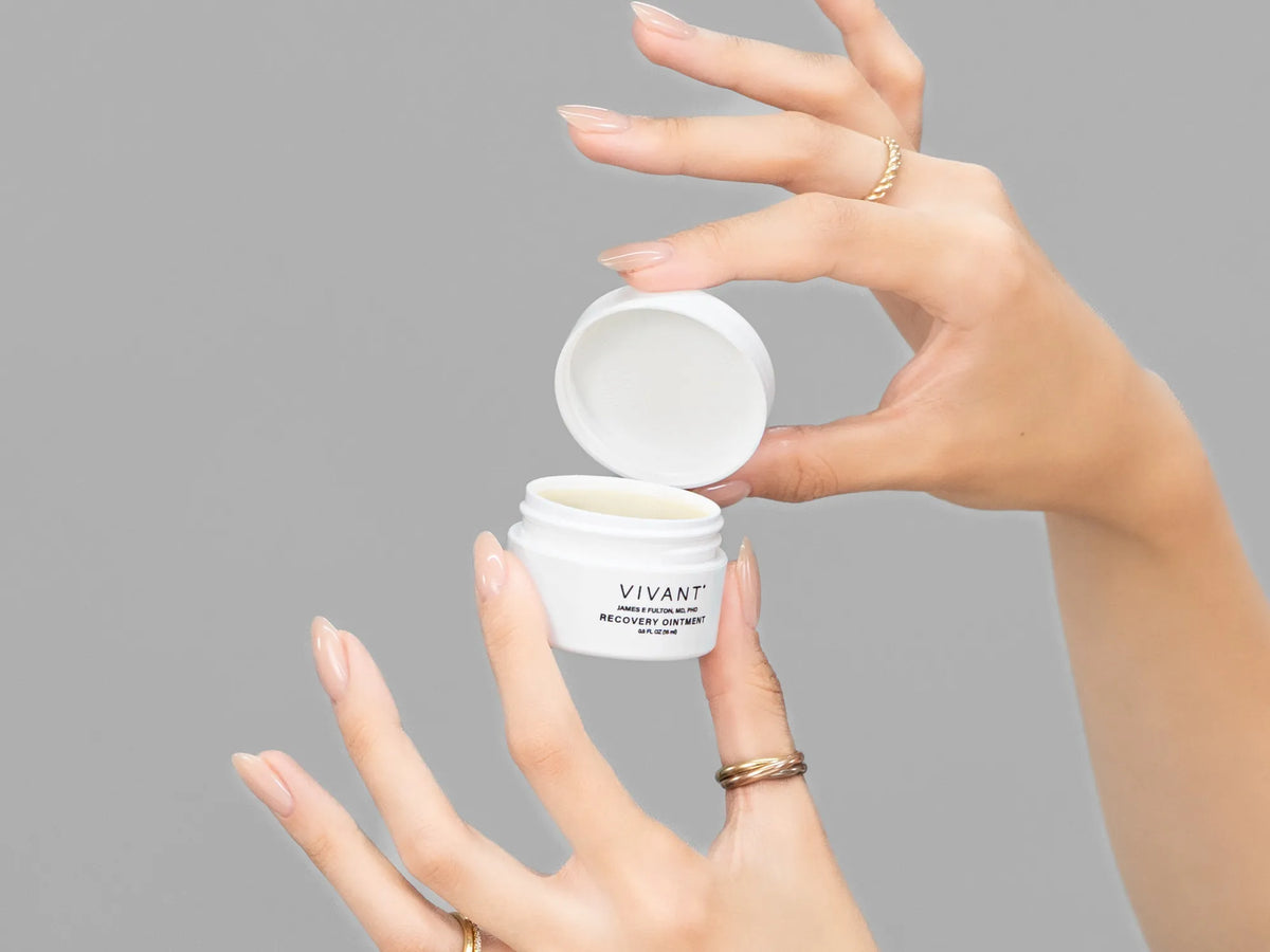 Closeup of Laziza from LAZ Skincare holding up a bottle of Vivant Recovery Ointment
