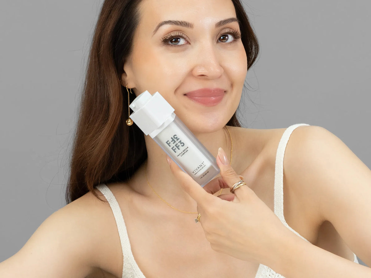 Laziza from LAZ Skincare holding a bottle of Vivant FF3 Triple Repair Complex up to her face