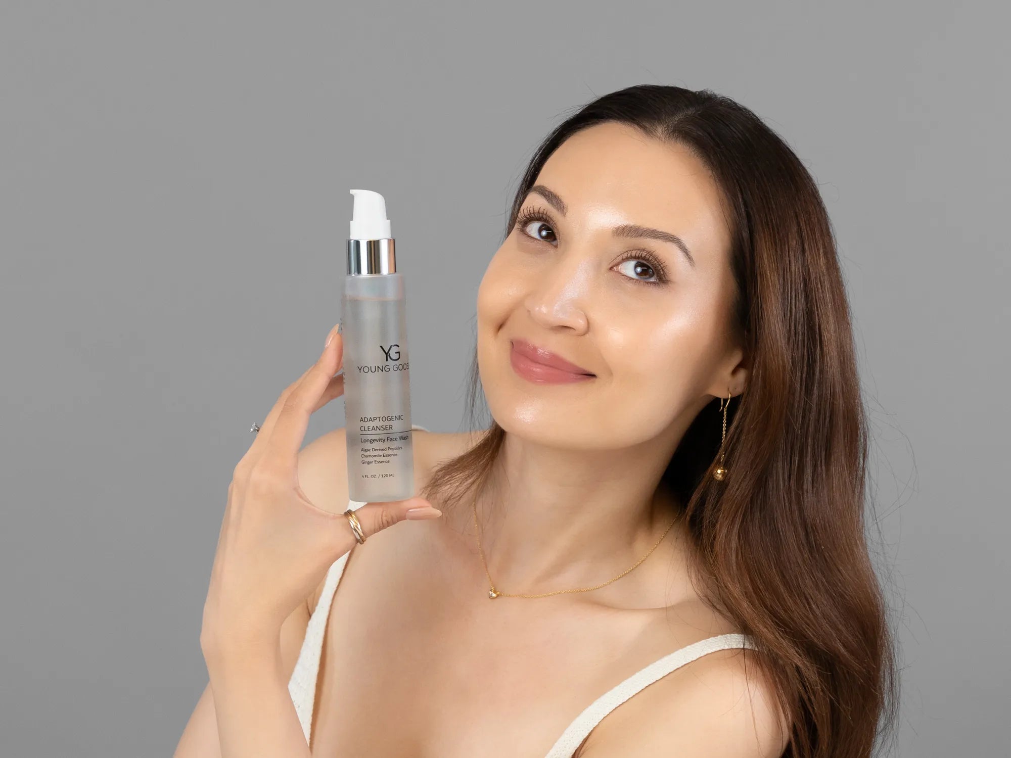 Laziza from LAZ Skincare holding a bottle of Young Goose Adaptogenic Cleanser up to her face