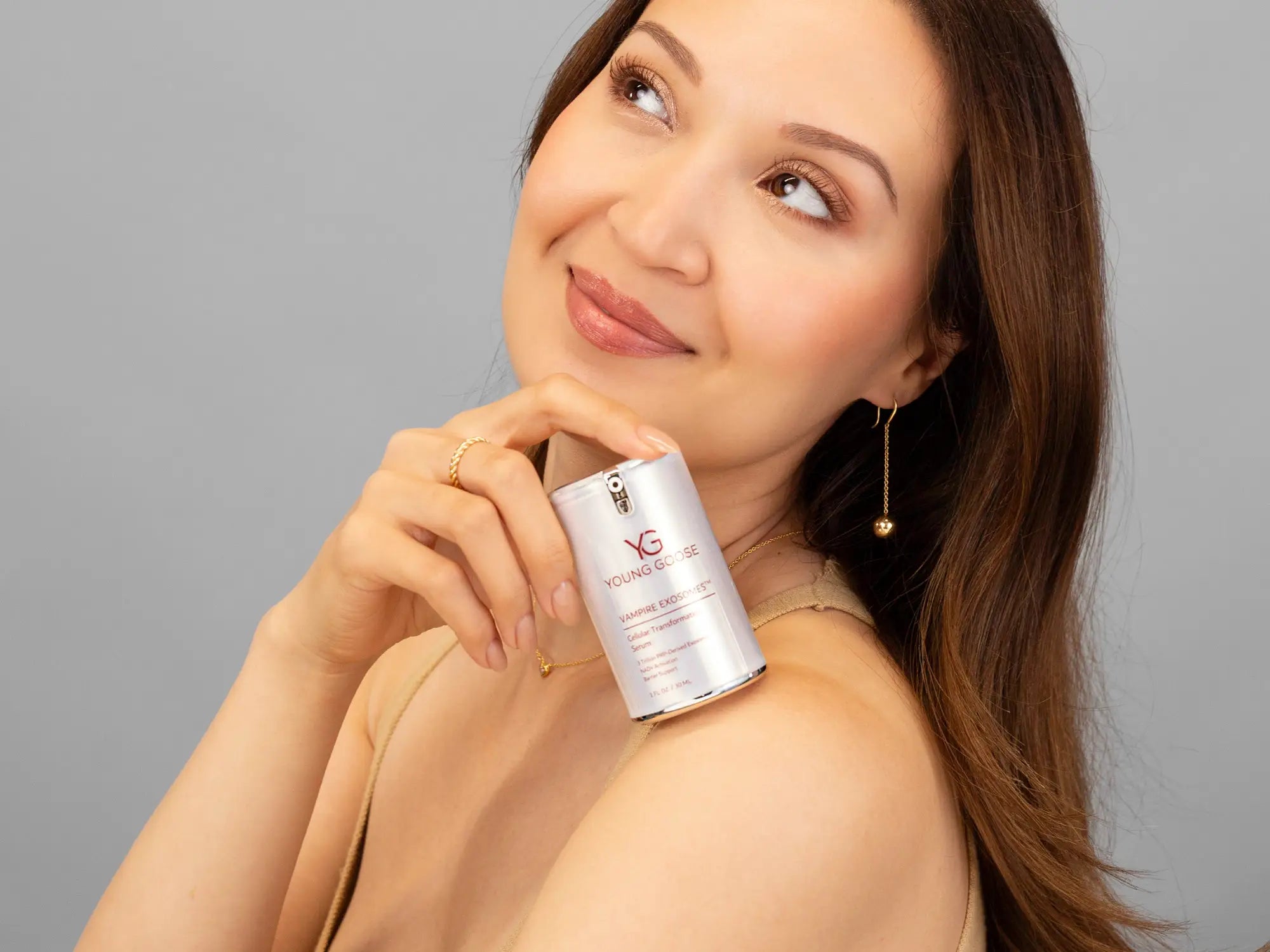 Laziza from LAZ Skincare holding a bottle of Young Goose Vampire Exosomes up to her face