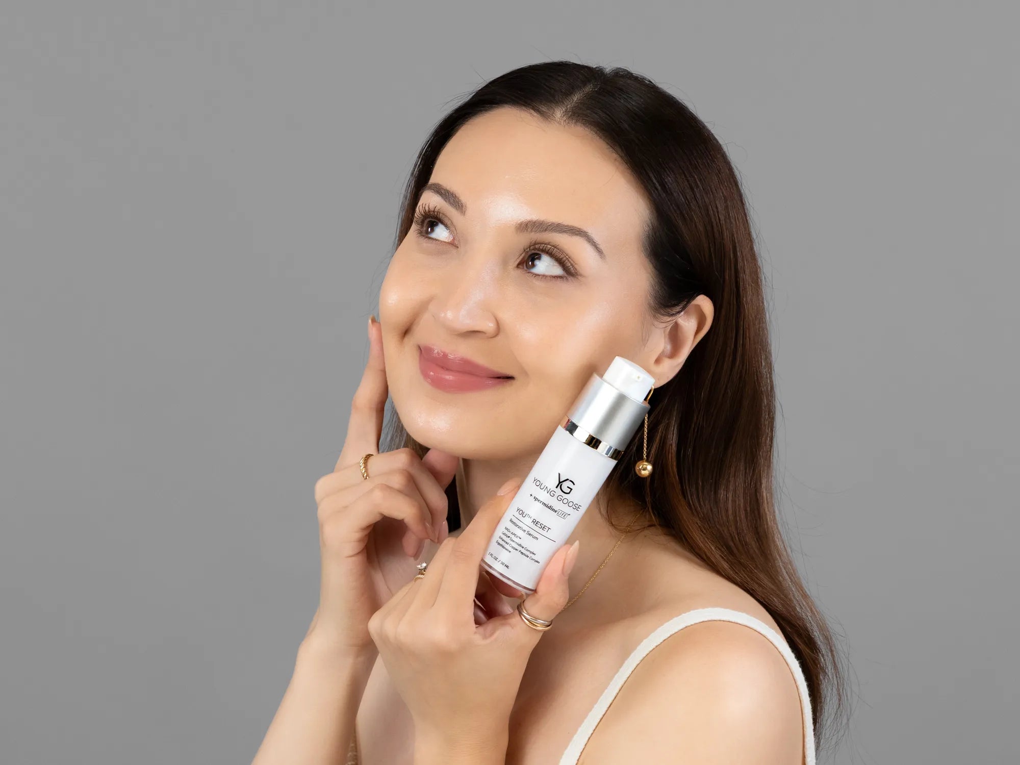Laziza from LAZ Skincare holding a bottle of Young Goose Youth Reset up to her face