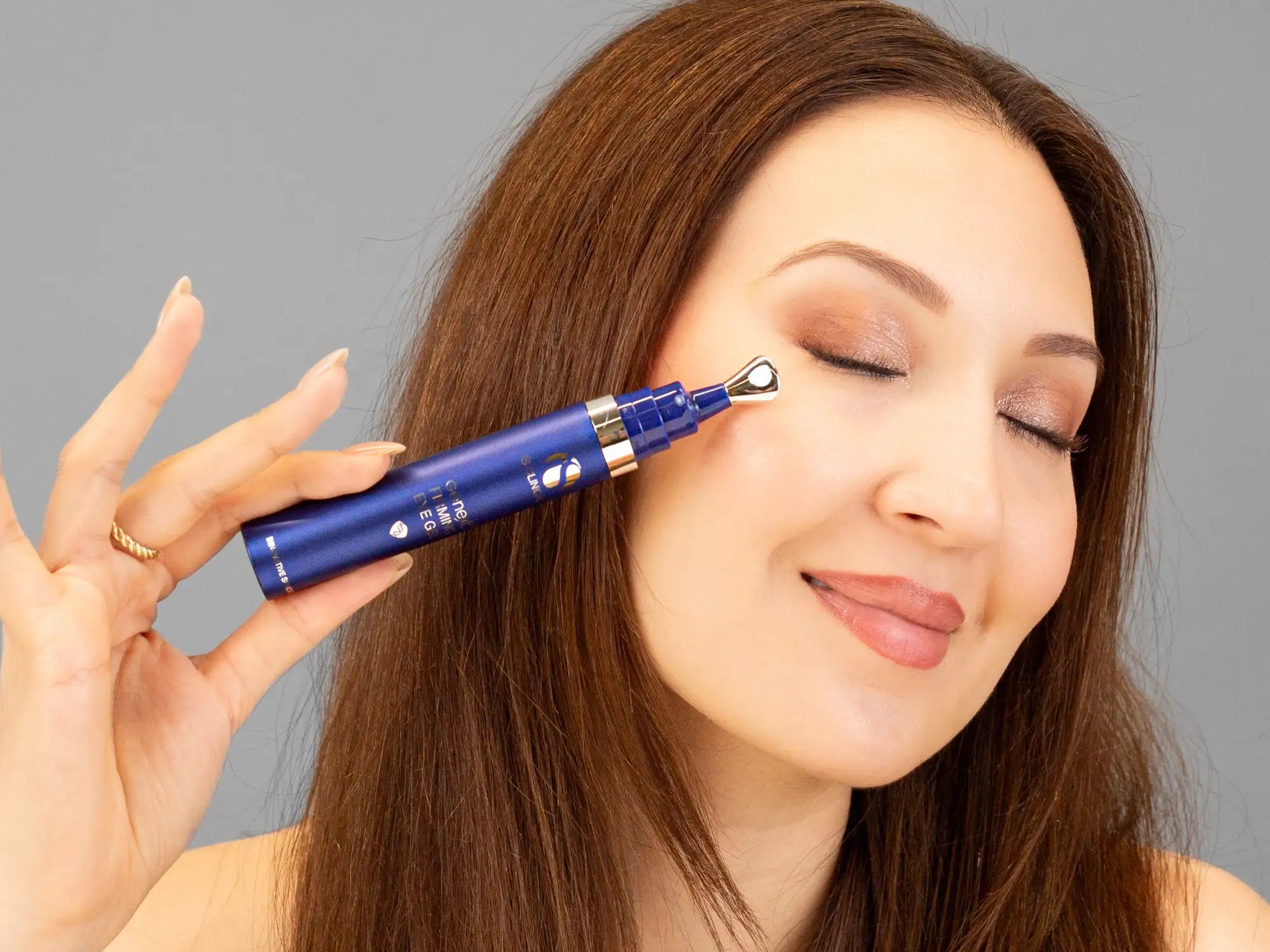 Laziza from LAZ Skincare holding a bottle of iS Clinical GeneXC Firming Eye Gel up to her face