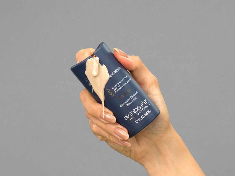 Closeup of Laziza from LAZ Skincare holding up a bottle of SkinBetter Science sunbetter TONE SMART SPF 75 Sunscreen Lotion